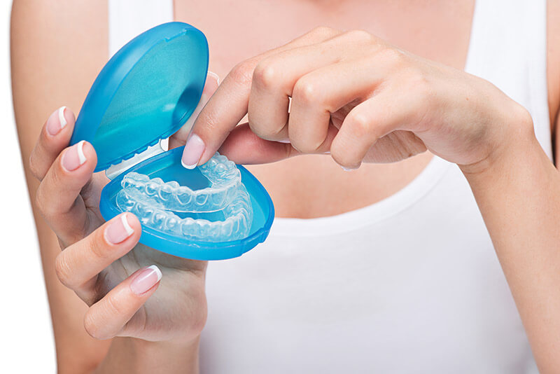 A person holding an invisible aligners inside a case